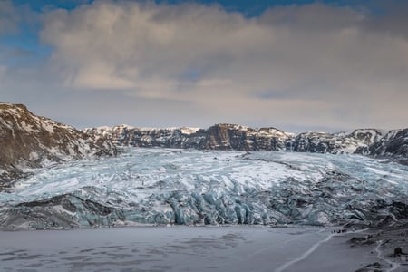 During a sunny day, the glacier of Sólheimajökull is perfectly reflecting on the peaceful waters.