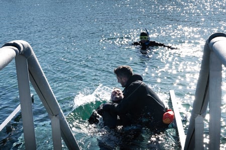 A client is being pulled out of the water by the diving instructor