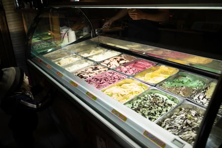 A small child is looking at a colorful display of icecreams in Efstidalur