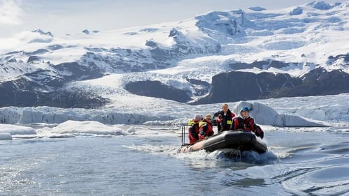 Zodiac boat navigating between massive blue icebergs in Fjallsárlón lagoon