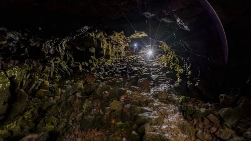 Underground adventurers exploring dramatic Raufarhólshellir lava tunnel formations