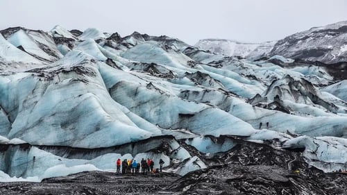 Hikers with crampons exploring Sólheimajökull glacier ice formations