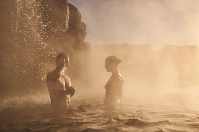 A nig puddle of mud, among sulfur colored rocks is boiling