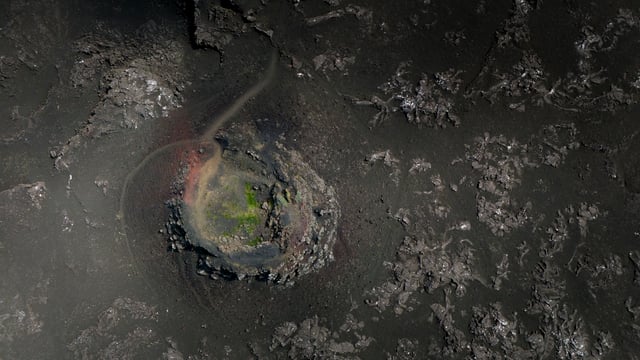 A volcanic crater with green vegetation inside seen from above