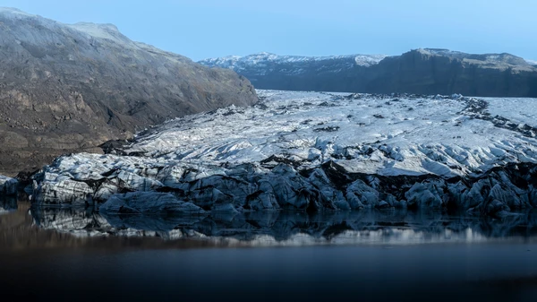 During a sunny day, the glacier of Sólheimajökull is perfectly reflecting on the peaceful waters.