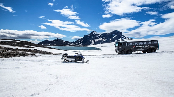 Line of snowmobiles crossing vast glacier landscape