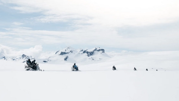 Snowmobile guide explaining glacier features to tour group