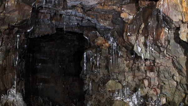 Professional caving guide leading small group through dramatic tunnel sections