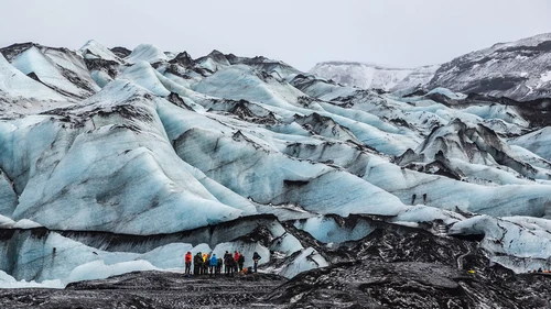 Hikers with crampons exploring Sólheimajökull glacier ice formations