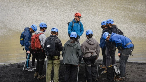 Small group of hikers exploring Sólheimajökull glacier ice formations