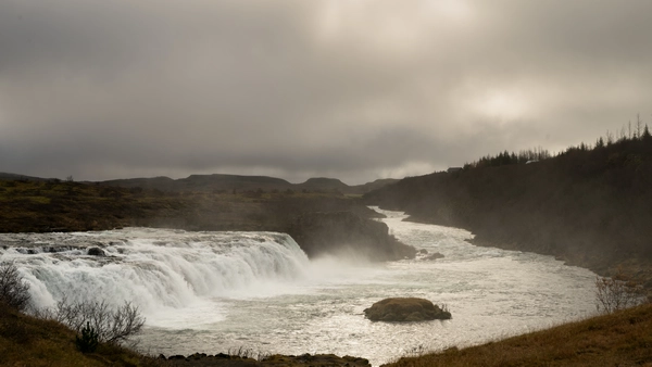 A man is fishing in front of a beautiful icelandic waterfall
