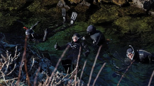 People are snorkeling in dry suit in the clearest waters in the world in Silfra in the National Park of Þingvellir