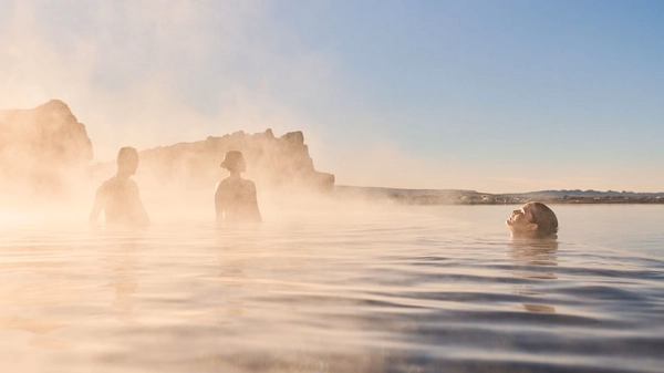 A nig puddle of mud, among sulfur colored rocks is boiling