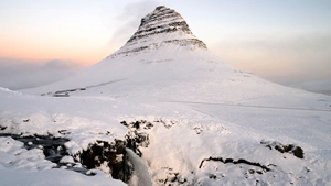 The Mount Kirkjufell in front of a partially frozen waterall - Snæfellsnes small group tour